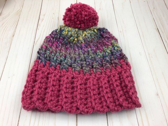 A photo of a crocheted unisex winter hat with a wooden background