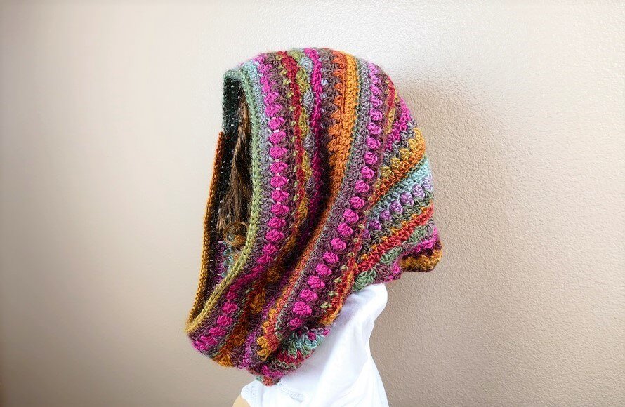 Photo of a side view woman wearing the crocheted Sweet Harmony Hooded Cowl