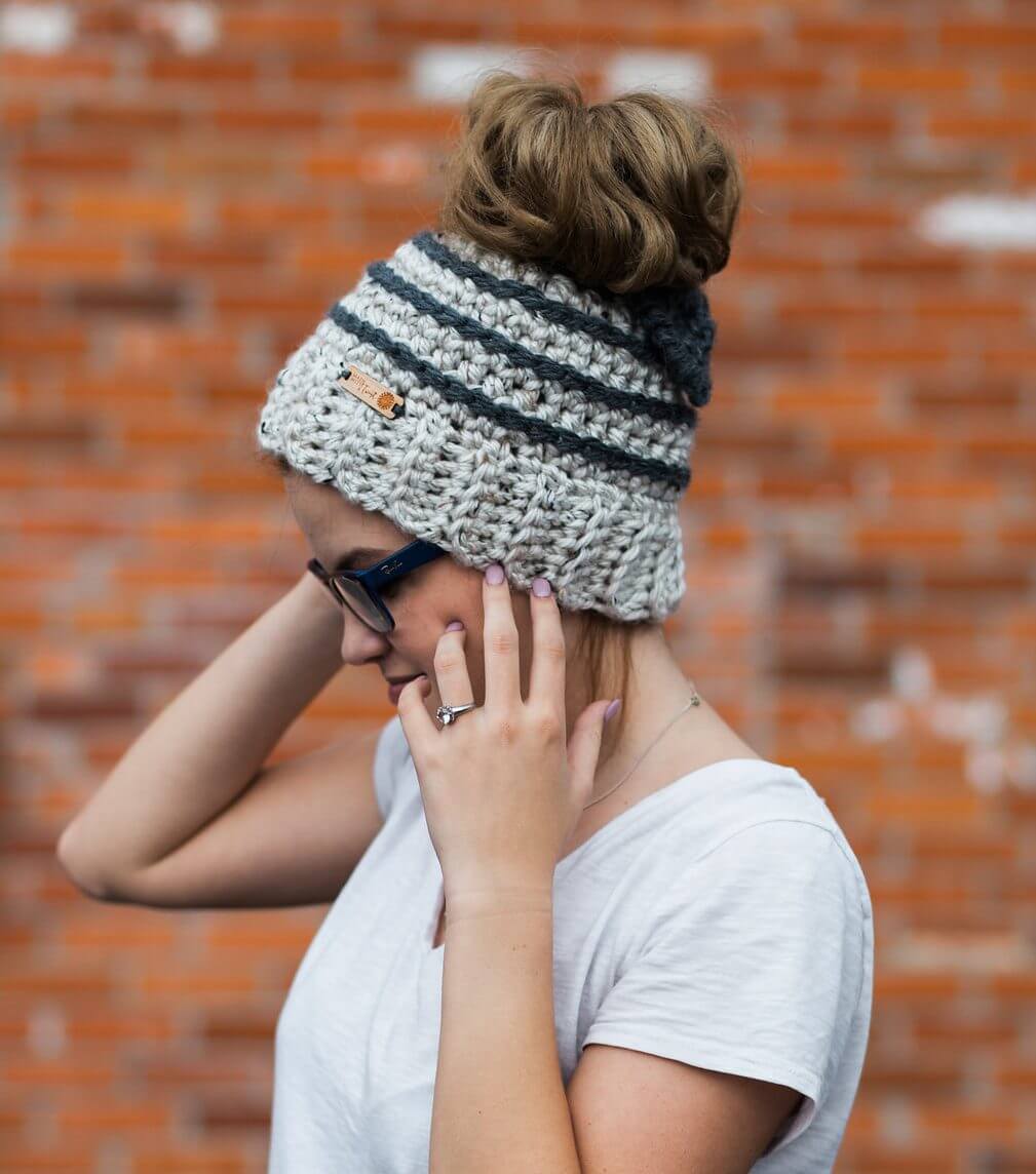 A woman wearing a white shirt and the Beehive Striped Messy Bun Beanie with Bow