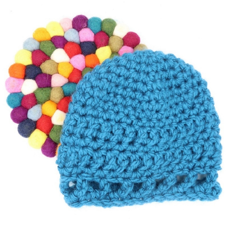 Photo of the blue Peek-a-boo Baby Hat with a colorful coaster at the back
