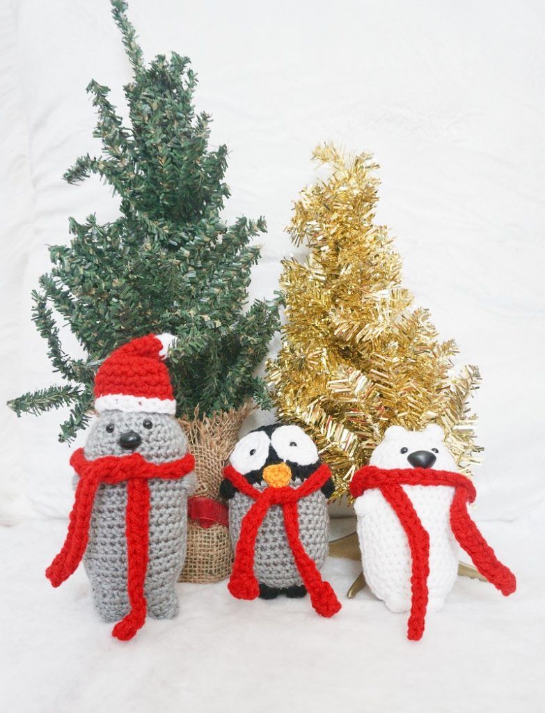 Photo of Amigurumi crochet seal, penguin, and polar bear in front of Christmas ornaments
