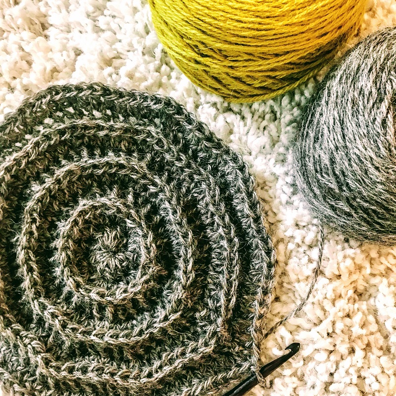 Close up photo of the unfinished hat with hook and yarns