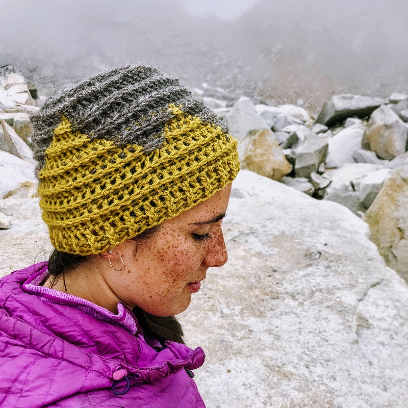 Photo of a woman wearing the FREE crochet beanie pattern while she is in the rocky outdoors