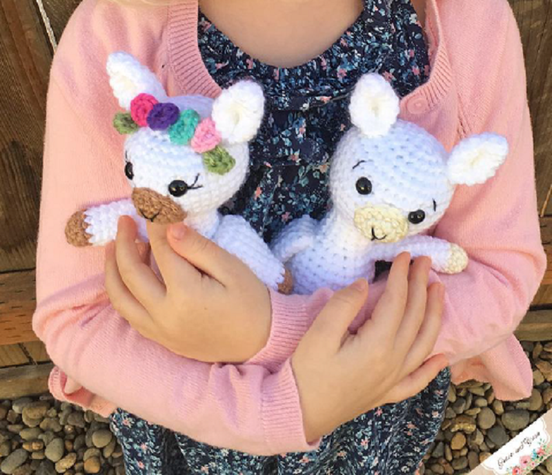 Photo of a girl holding miniature crocheted baby llama stuffed toys
